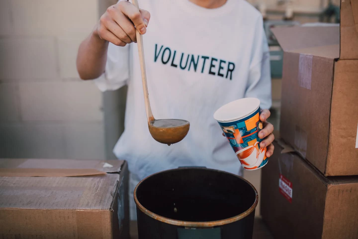 A volunteer serving a warm meal from a large pot