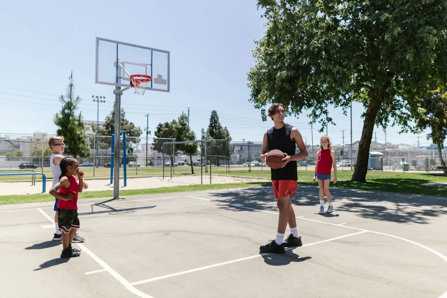 Young people practicing basketball with a coach outdoors