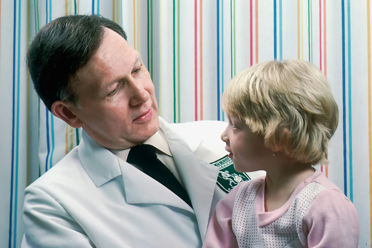 A physician speaking with a child in a clinical setting