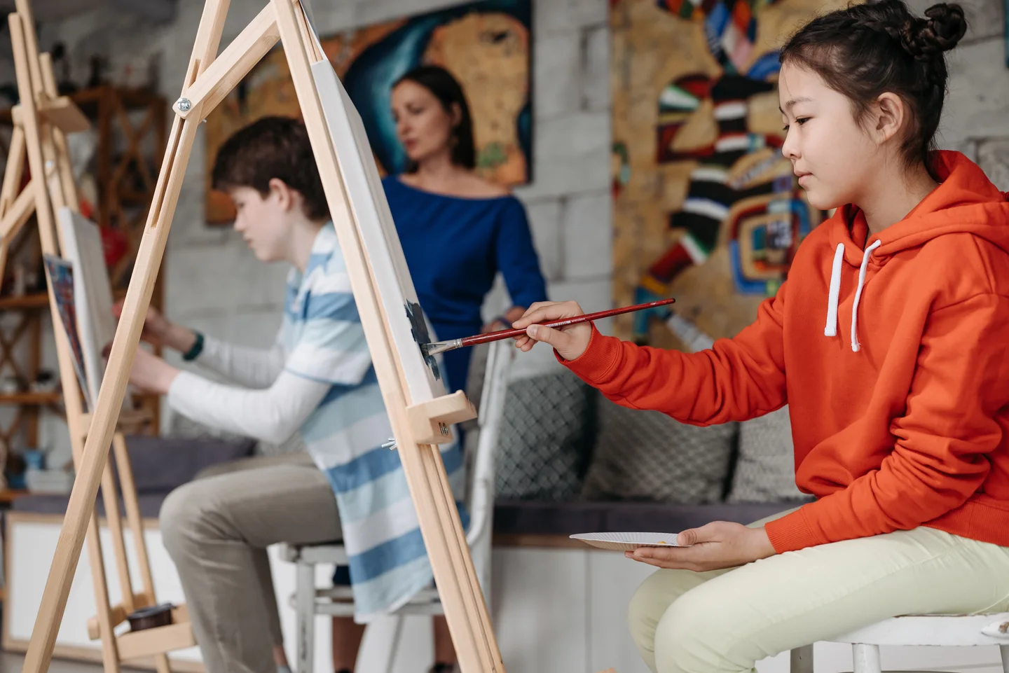 Young students painting at easels with a teacher